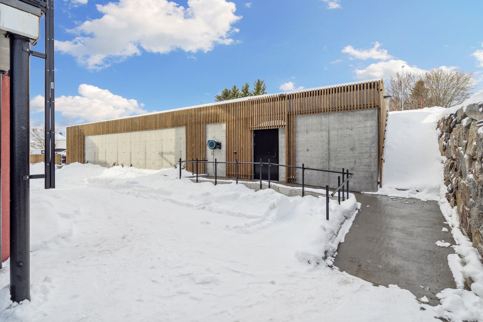 Fra inngangspartiet går du enkelt inn i felles garasje- og bod anlegg. Det er også laget til en smart sherpatrapp mellom garasjen og steinmuren, slik at du effektivt kommer deg i retning av sentrum og lysløpa. Galleribilde