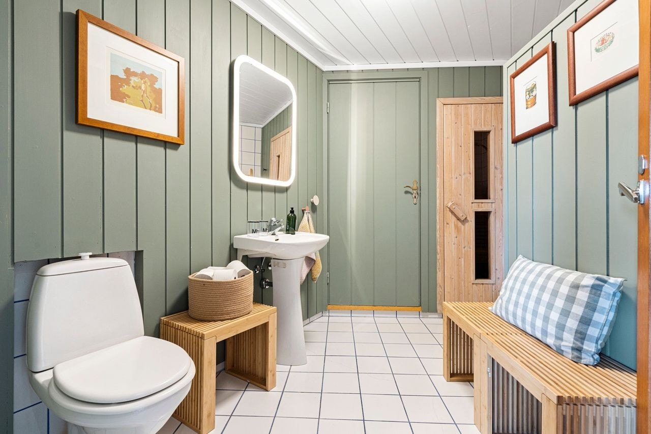 Delikat baderom som står i tidsriktige farger, og inneholder dusjhjørne, gulvmontert toalett og servant. Det er vaskemaskin på badet. Galleribilde