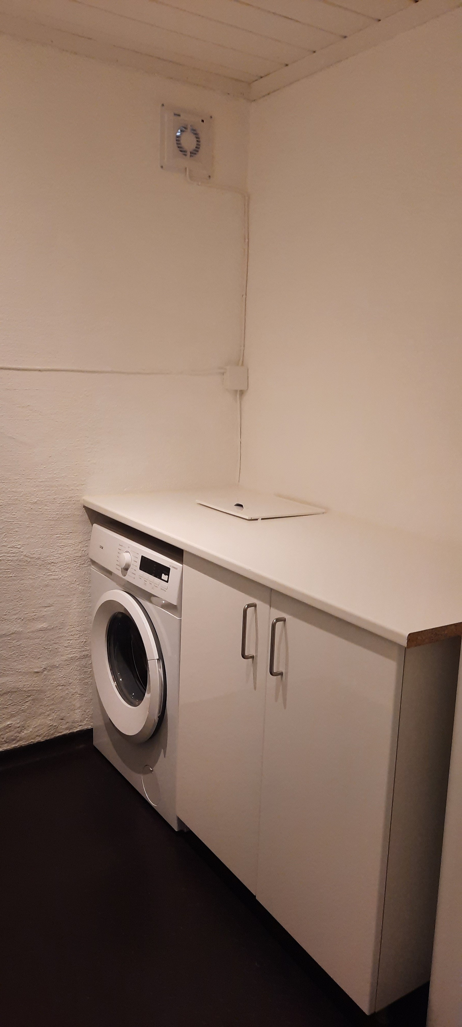 Romslig vaskerom med vaskemaskin og oppbevaring Galleribilde