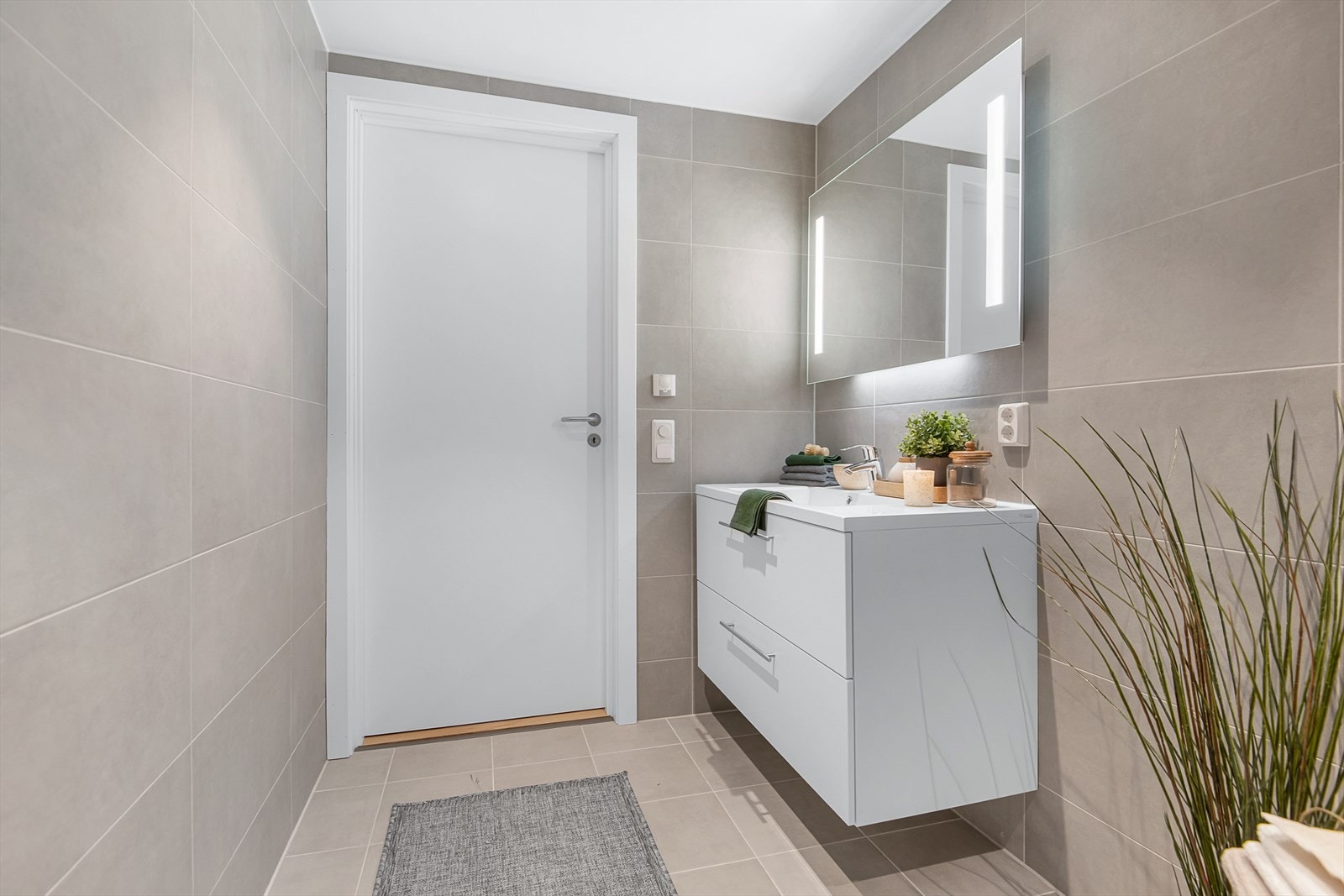 Tidløs baderomsinnredning og speil med integrerte lysfelt over servant. Varme i gulv også her. Galleribilde