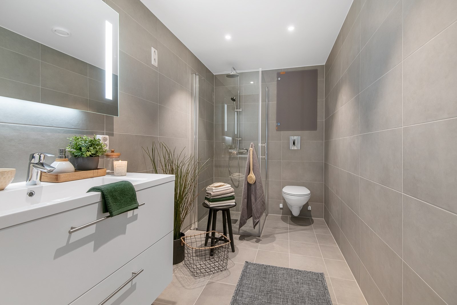Baderommet er delikat innredet med flis i lys grå utførelse på gulv og vegg samt downlights i himling.
NB: Bildet er fra en annen leilighet med likt baderom. Galleribilde