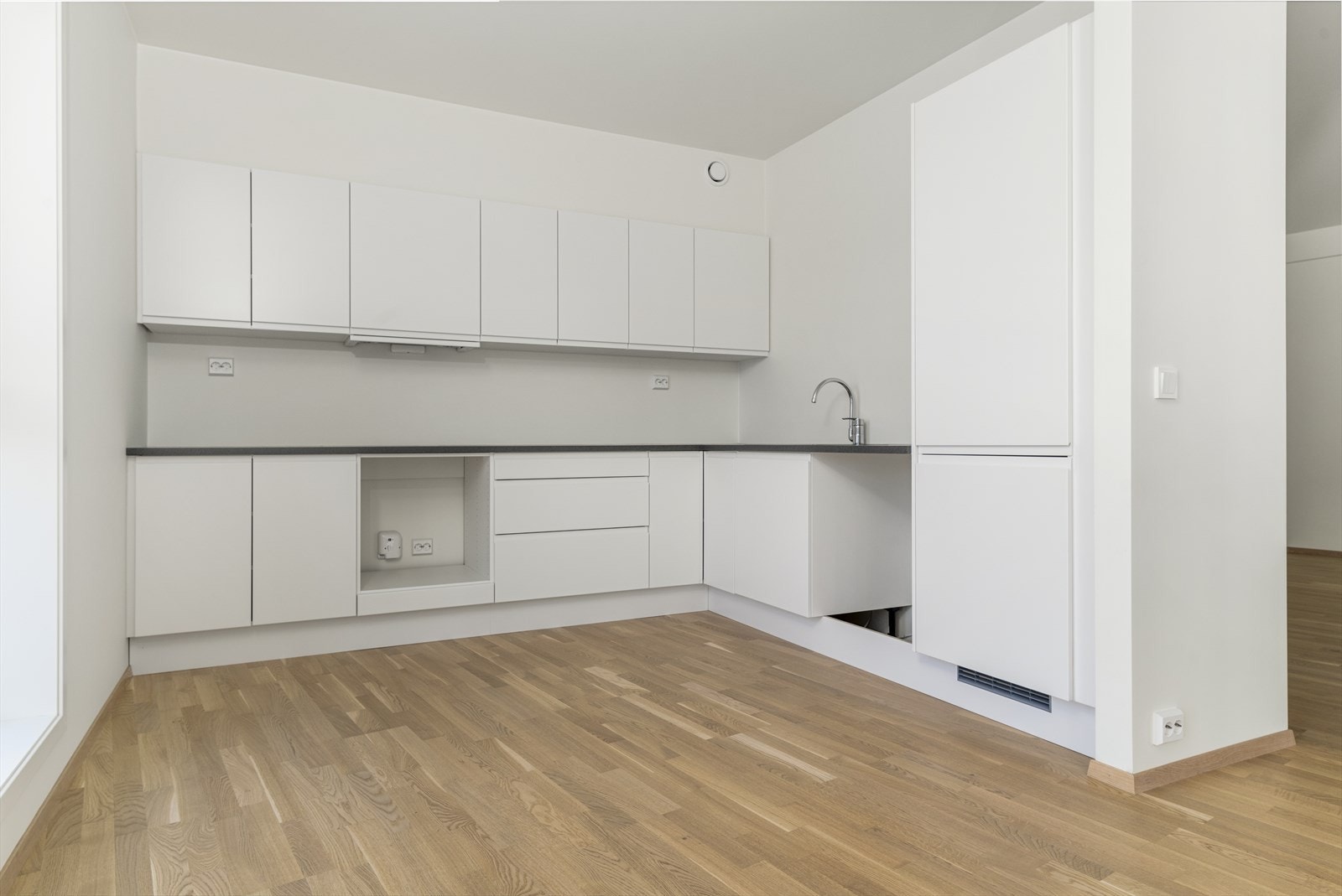 Kjøkken og stue i åpen løsning, men kjøkkenet er samtidig trukket litt bort. Lys og moderne kjøkkeninnredning fra Norema Galleribilde