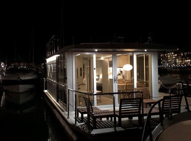 Flytende mini-hus, kalles husbåt eller bo-båt, 2 soverom, stue kjøkken, nå liggende på leid plass i Oslo. Galleribilde