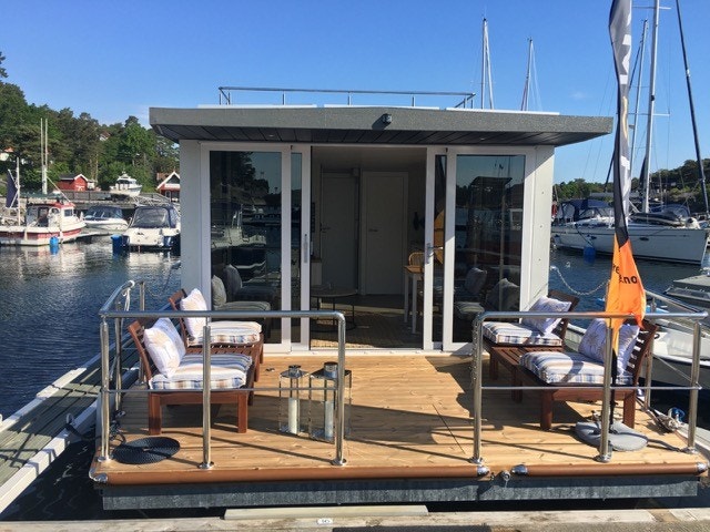 Flytende mini-hus, kalles husbåt eller bo-båt, 2 soverom, stue kjøkken, nå liggende på leid plass i Oslo. Galleribilde