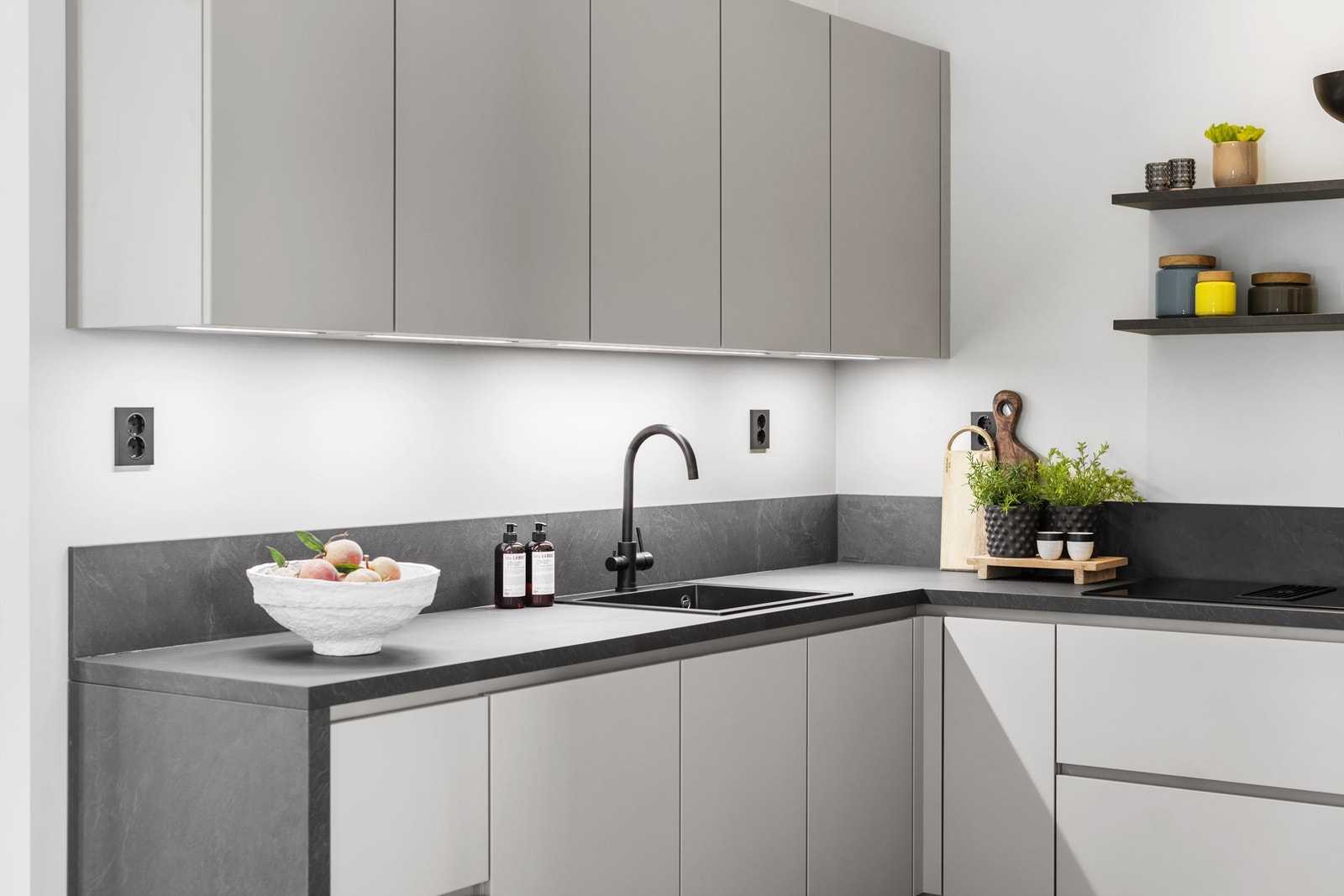 Det er innebygget belysning under overskap og hylleplan over induksjonstopp Galleribilde