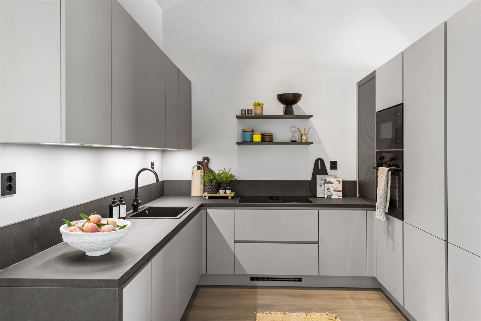 Stilrent kjøkken med innredning i slette, skifergrå fronter, laminert benkeplate og integrerte hvitevarer Galleribilde