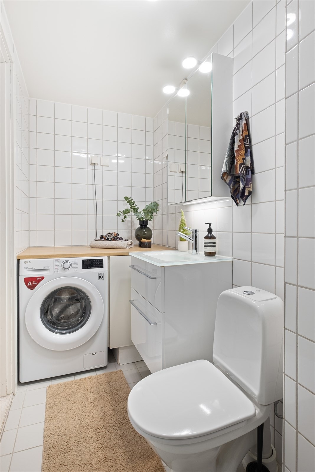 Badet har innredning og garnityr som består av bereder, dusjhjørne med innfellbare dusjdører, gulvstående toalett og servantinnredning med skuffer, speilskap og nedfelt servant Galleribilde