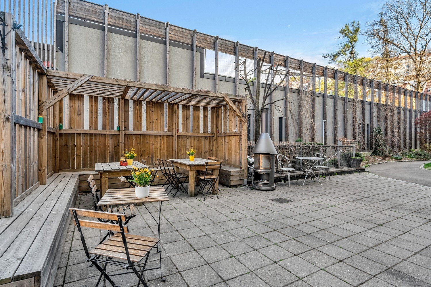 Utearealet er pent opparbeidet med sittegrupper, beplantning og brostein Galleribilde