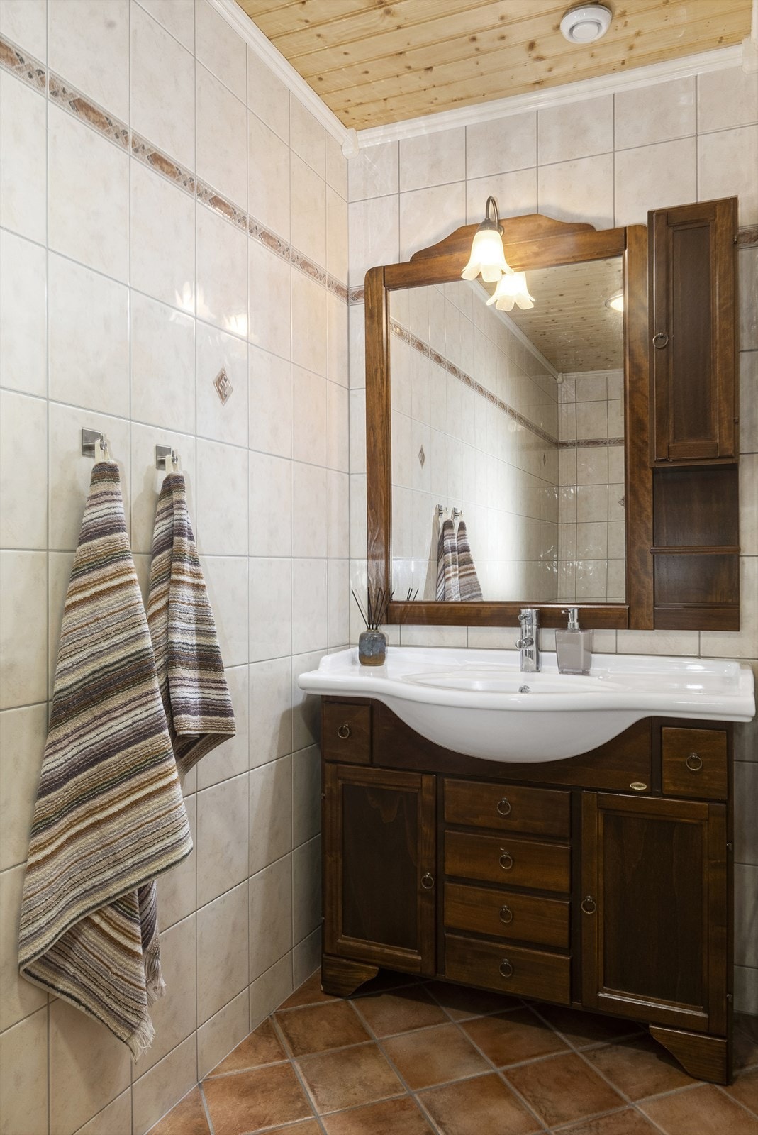 Badet har benk med heldekkende vask, et overskap, speil, toalett og dusjhjørne. Galleribilde