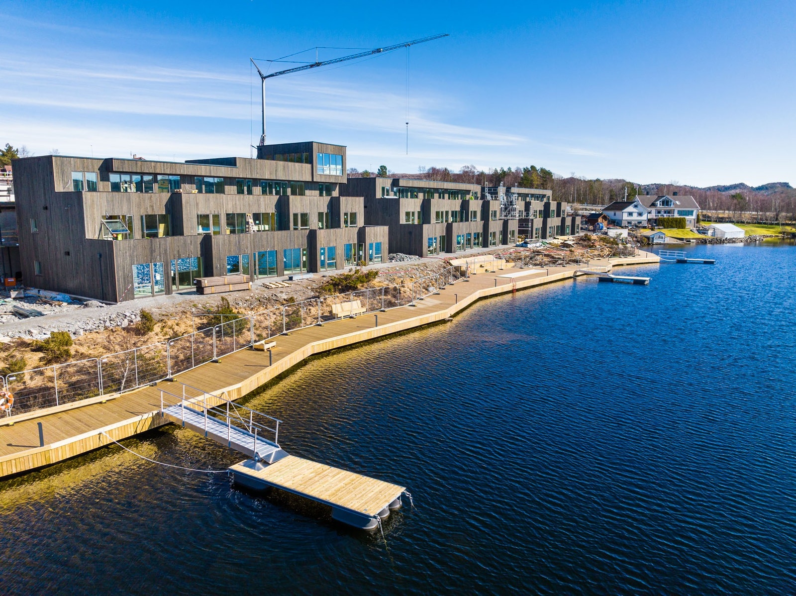 Promenande og Vannkanten. Bak Vannkanten bygges Skogkanten. 1. etg i Skogkanten går i linje med takterrasse Vannkanten. Det vil fin bli utsikt over Aksdalsvatnet! Galleribilde