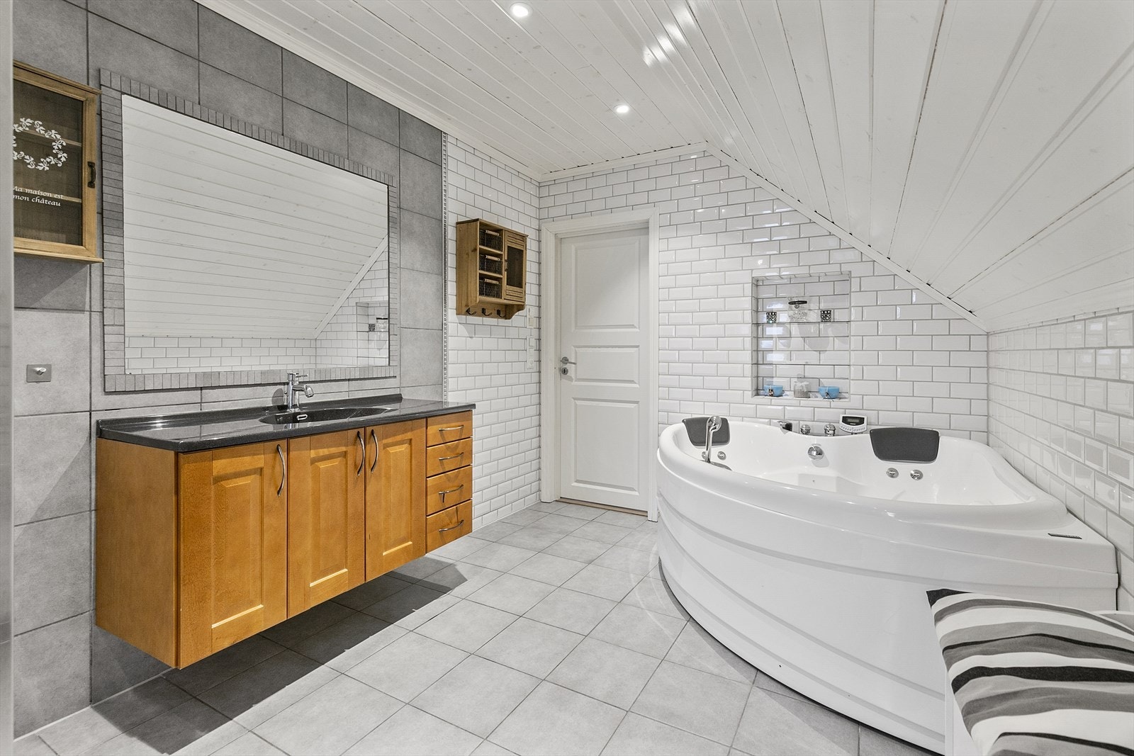 Badet er stilfullt med mange detaljer. Servantskap og stort speil kledd inn med fliser. Over boblebadet er innebygd hylle med glassplate. Her er det bare å dimme ned downlights, tenne stearinlys og nyte spafølelsen Galleribilde