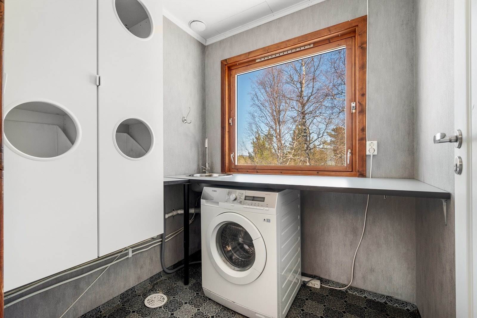 Det er også et eget praktisk vaskerom med våtromsbelegg på gulv, tapet på vegger og malte plater i himling Galleribilde