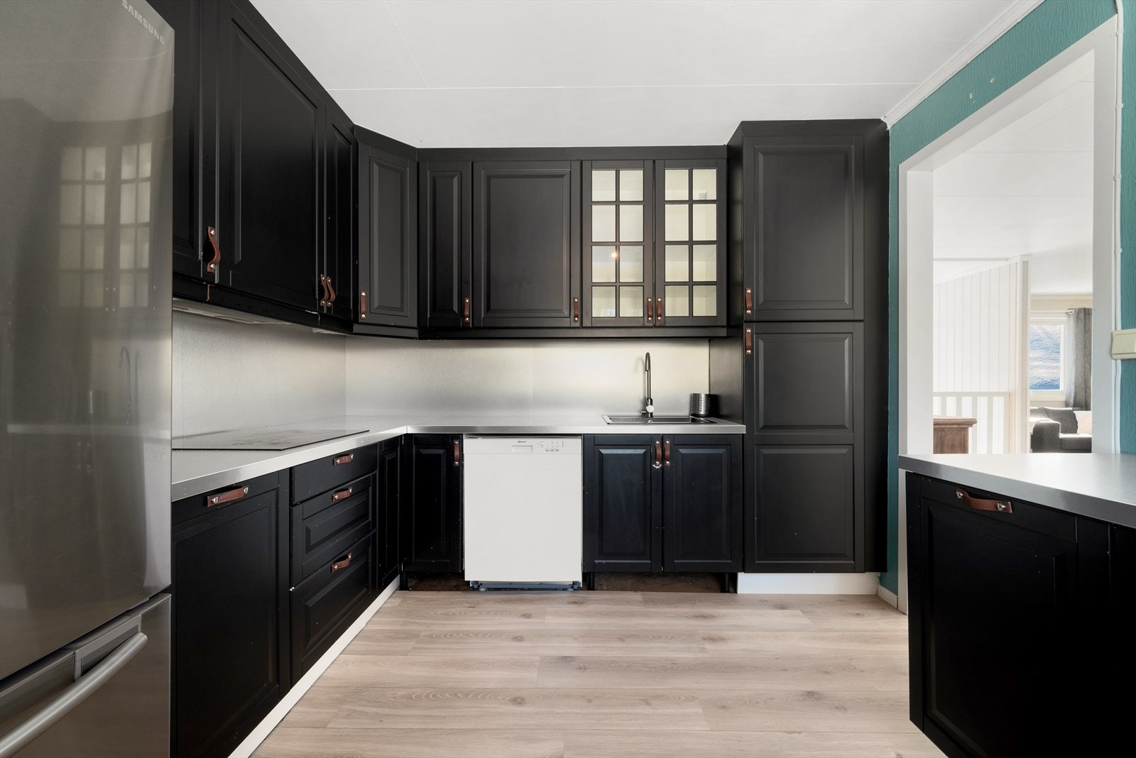 Profilerte fronter, laminat benkeplater, koketopp, oppvaskmaskin,
komfyr, og mekanisk avtrekksvifte over kokesone. Galleribilde