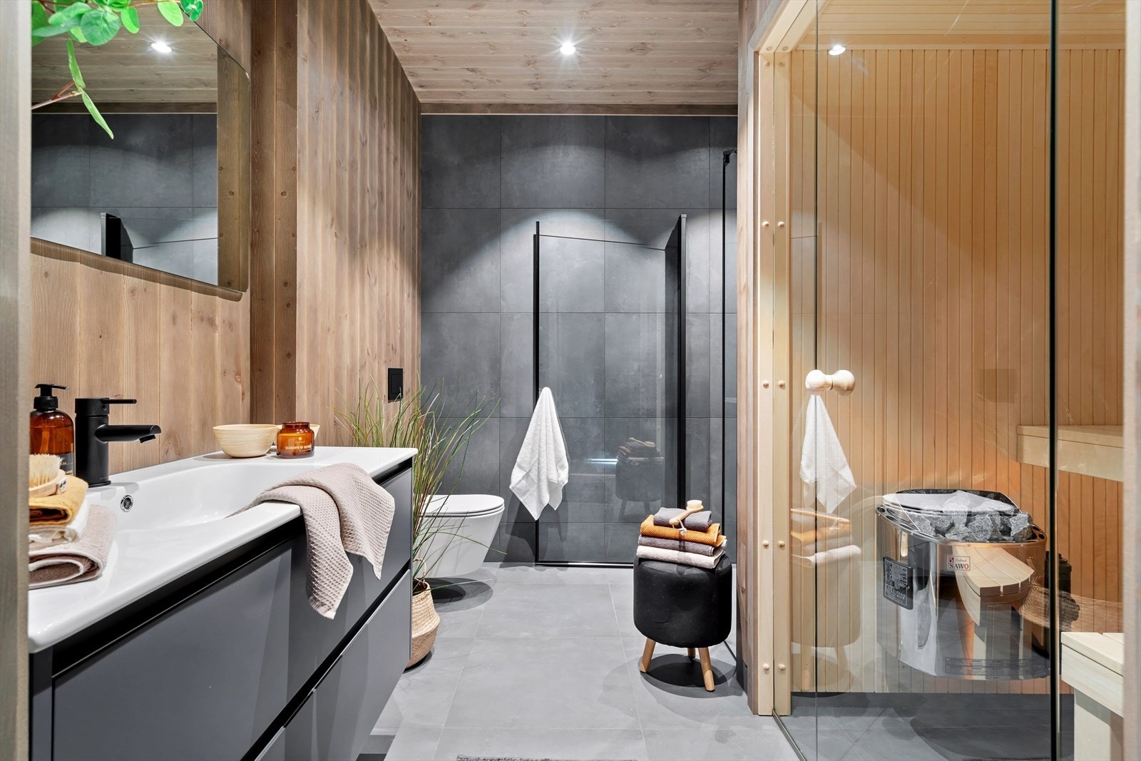 Baderomsinnredning med heldekkende hvit servant og svart armatur. Her finner man også en herlig badstue - perfekt etter en lang dag ski Galleribilde