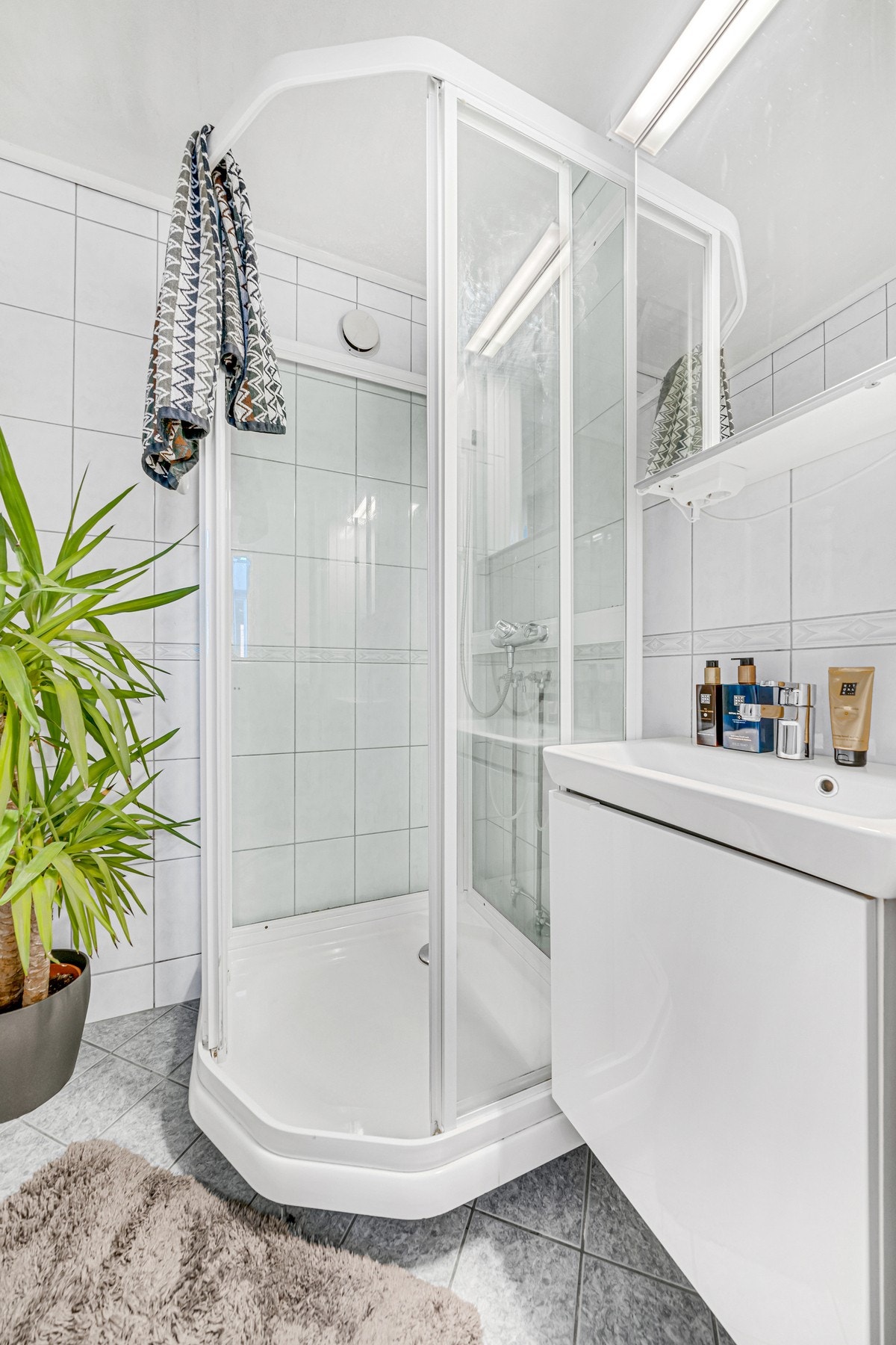 Lyst og flislagt bad med dusjkabinett og moderne innredning. Galleribilde