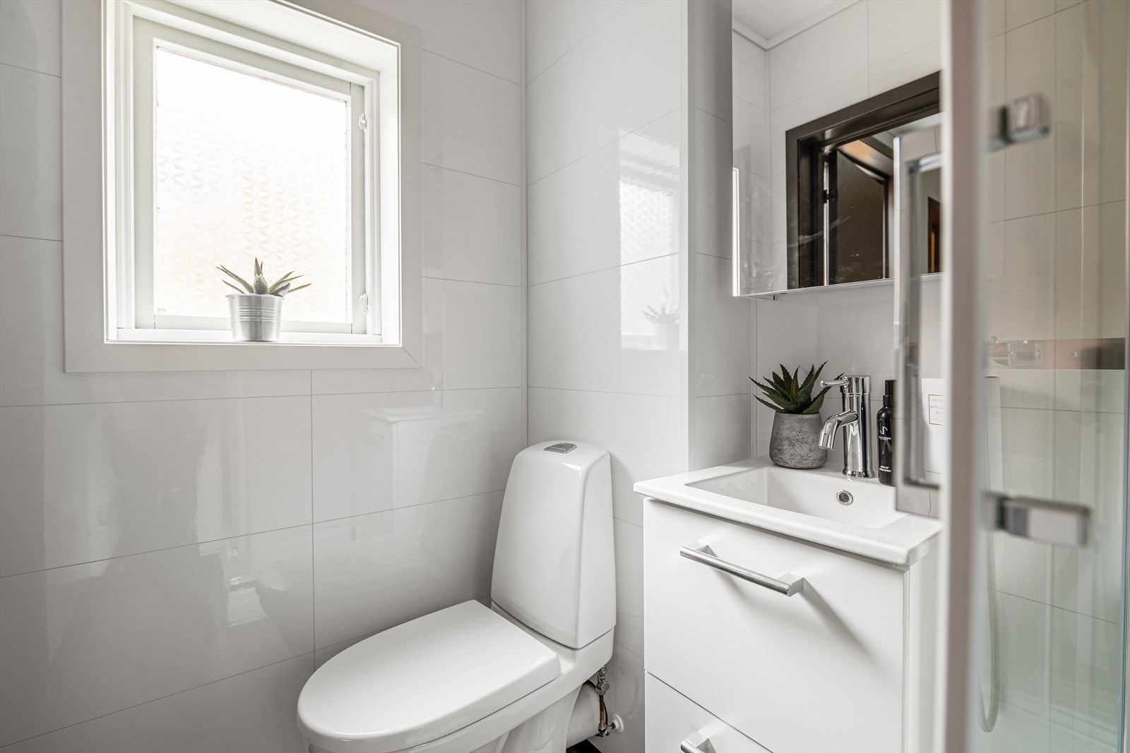 Baderomsinnredning av servant nedfelt i hvit innredning med to underskuffer og speilskap over. Galleribilde