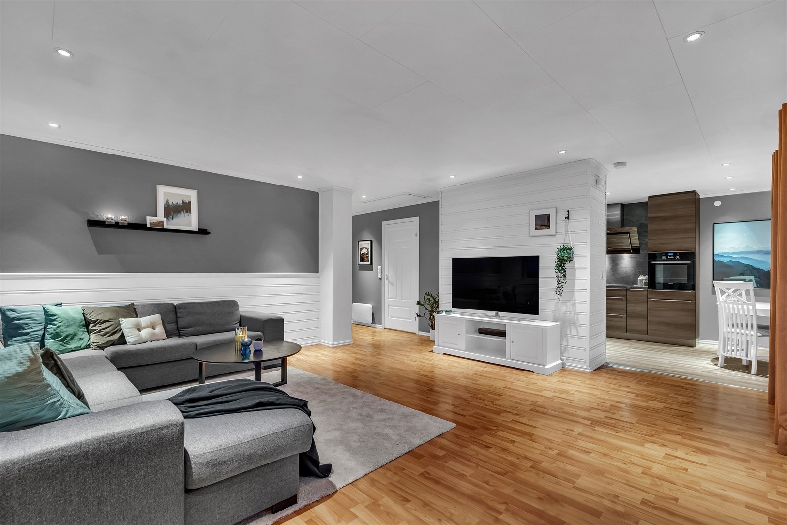 Laminatgulvet fra gangen flyter sømløst over til en fin og luftig stue med god plass til hjørnesofa og tv-benk. Galleribilde