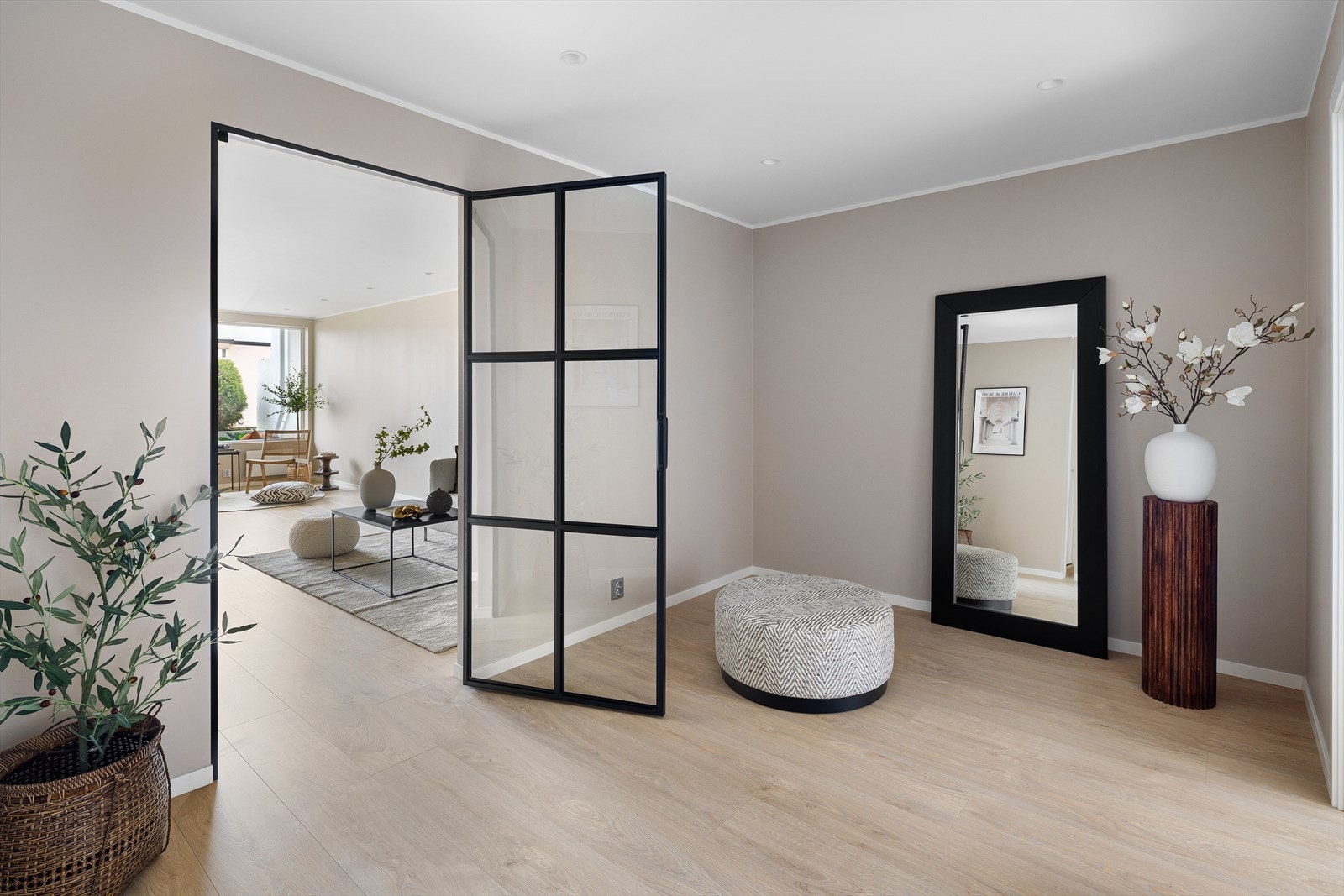 En tidsriktig, håndlaget industriglassdør av svart metall er installert inn mot stuen, en interiørdetalj som gir boligen karakter og ekstra romfølelse. Galleribilde