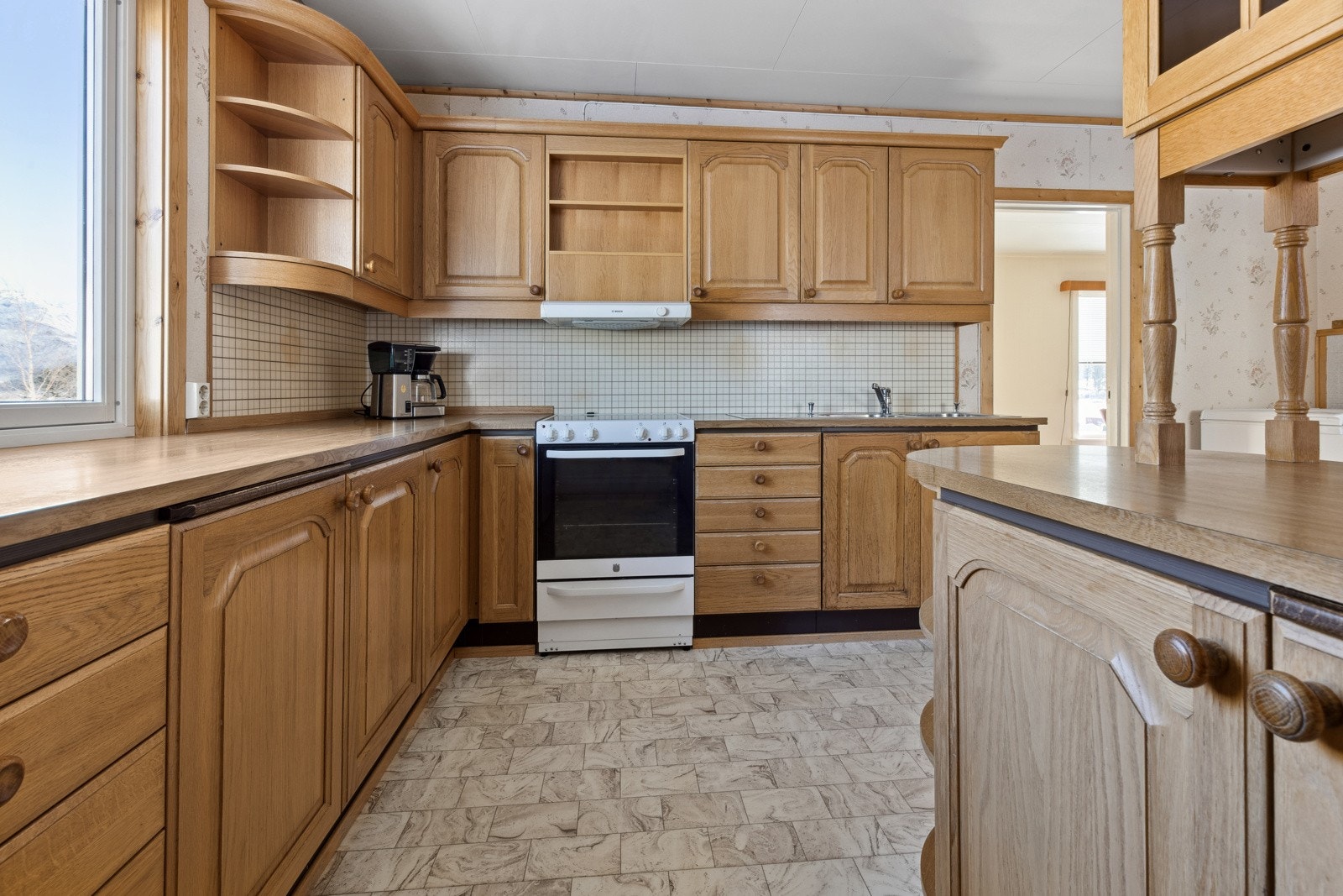 Kjøkkenet ligger i eget rom på enden av stuen, med innredning av profilerte eikefronter og laminat benkeplate. Galleribilde