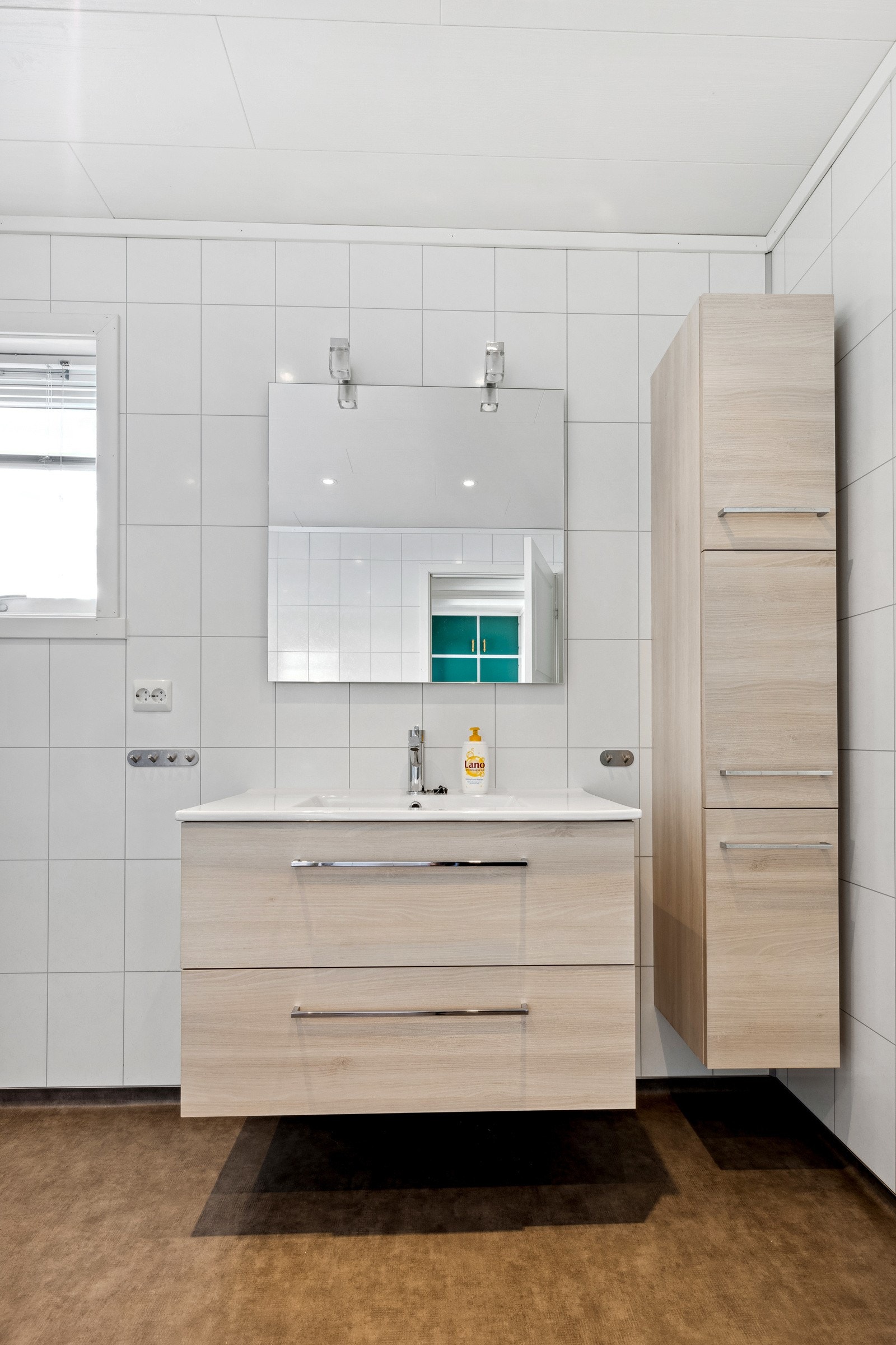 Badet er av god størrelse, med dusjnisje, gulvstående toalett, servant med skuffeseksjon og opplegg for vaskemaskin. Galleribilde