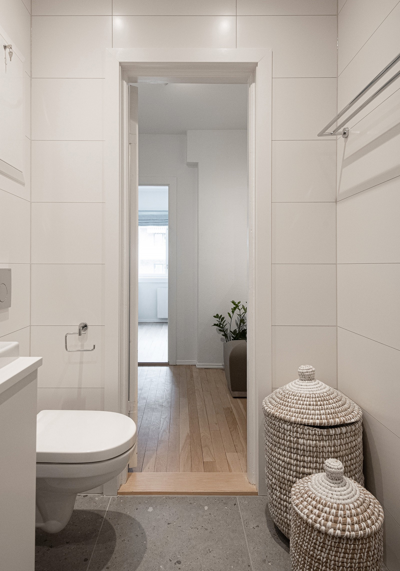 Baderommet har grå fliser på gulv med gulvvarme, hvite fliser på veggene og downlights i himlingen. Galleribilde
