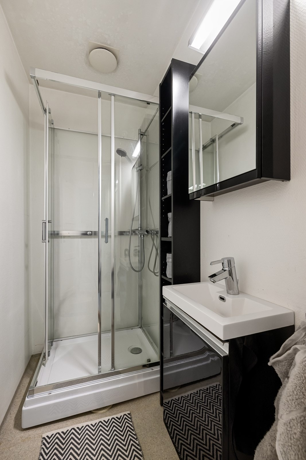 Badet er av eldre standard, men fungerer fint til sitt formål. Det er innredet med dusjkabinett av nyere årgang, servantskap og øvrig skapinnredning. Belysning over speilskap. Galleribilde