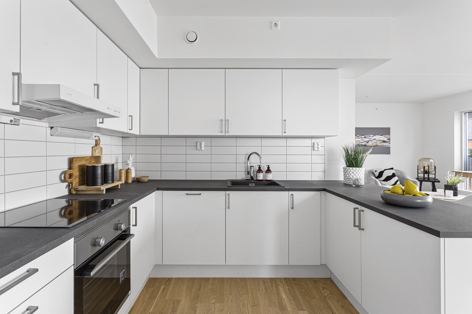 Laminat benkeplate og takhøye overskap i kombinasjon med integrerte hvitevarer som koketopp, stekeovn, oppvaskmaskin og kjøle-/fryseskap. Galleribilde