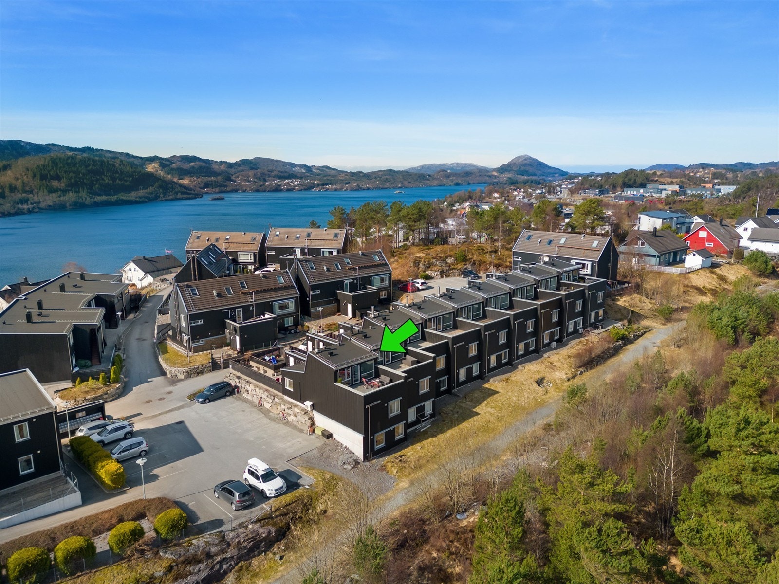 Dronebilde over rekkehuset hvor man ser boligens biloppstillingsplassen. Galleribilde