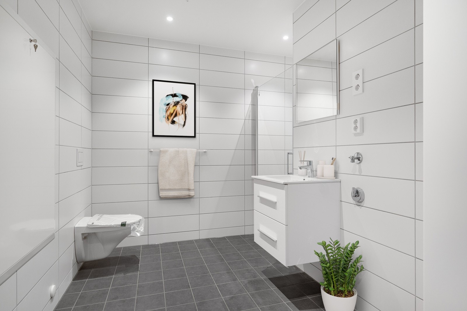 Badet har delikate fliser på gulv og vegger, gulvvarme, avtrekk, toalett, dusjhjørne og opplegg for vaskemaskin. Galleribilde