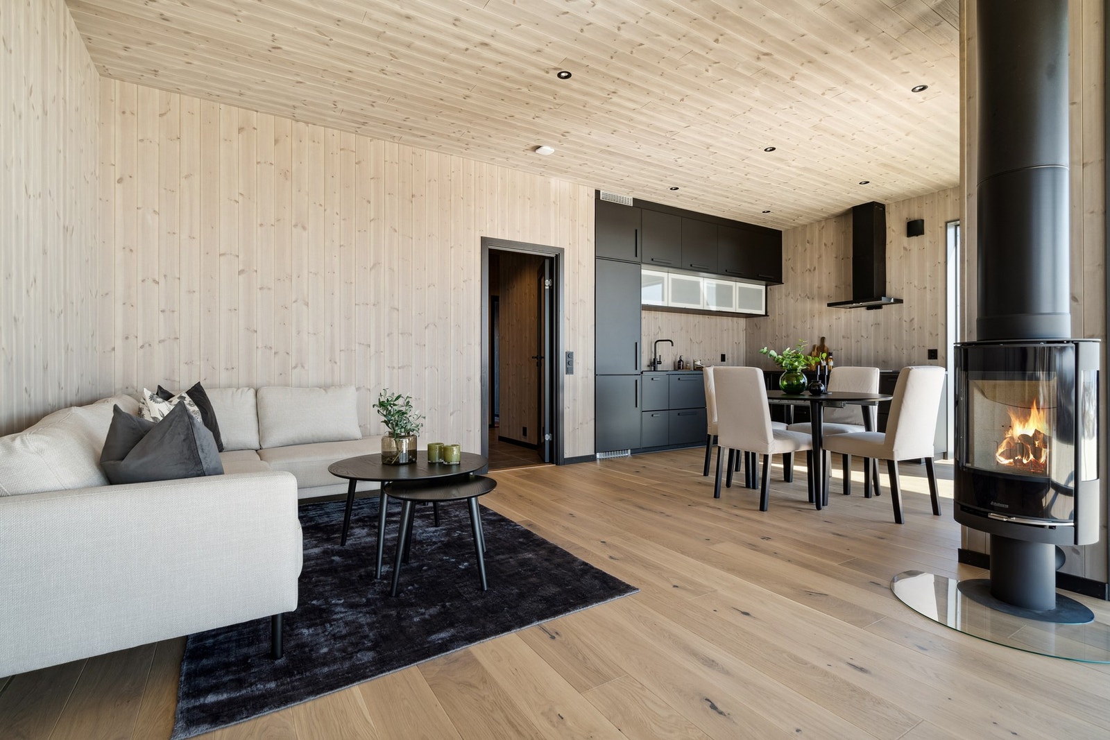 Stor stue og kjøkken som har et moderne "look" med parkett på gulv og panel på vegger og i tak. Det er også spotter i taket. Galleribilde