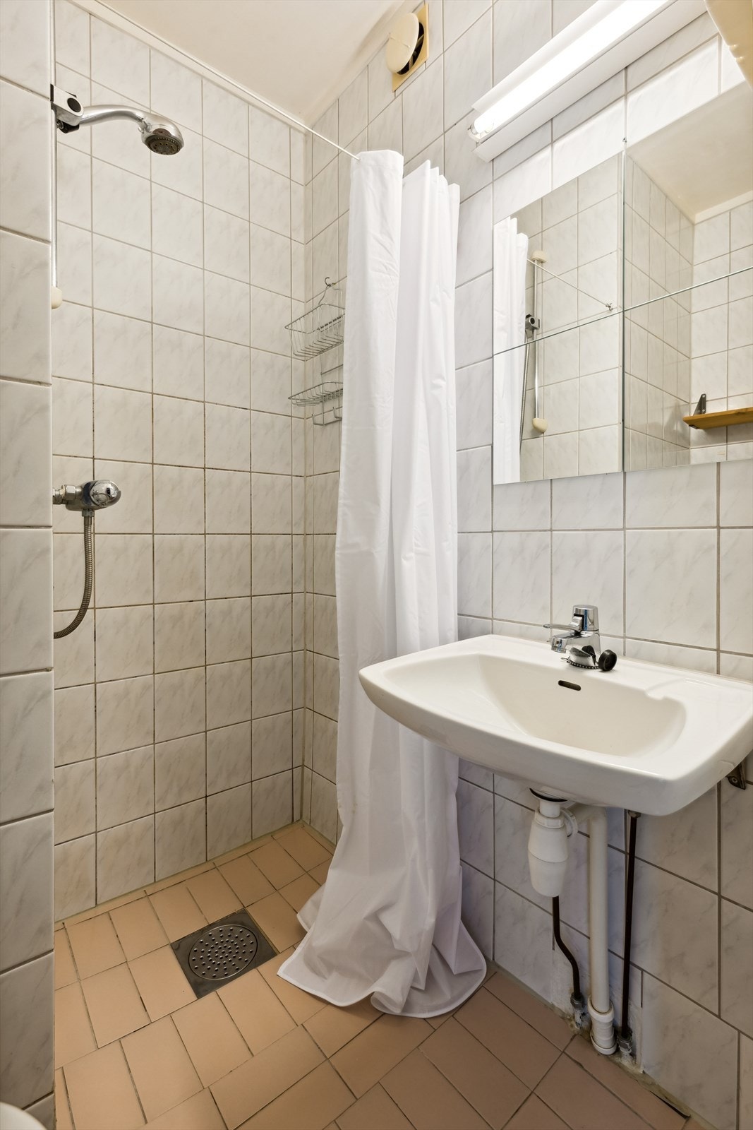 Badet er innredet med toalett, dusjnisje, servant og speil med overlys. Galleribilde