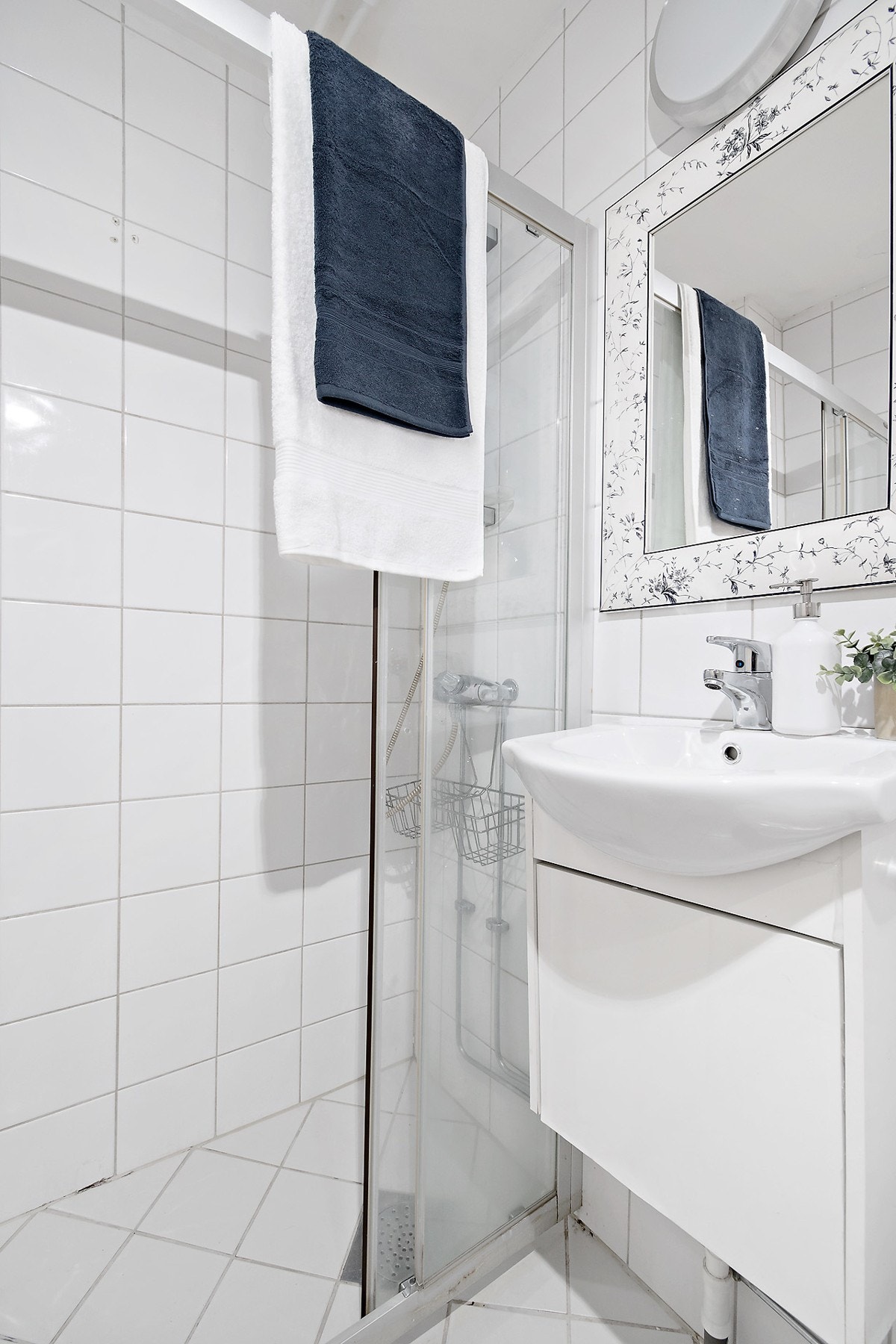 Badet er innredet med toalett, servantskap og dusj i hjørne med skyvedør. Galleribilde