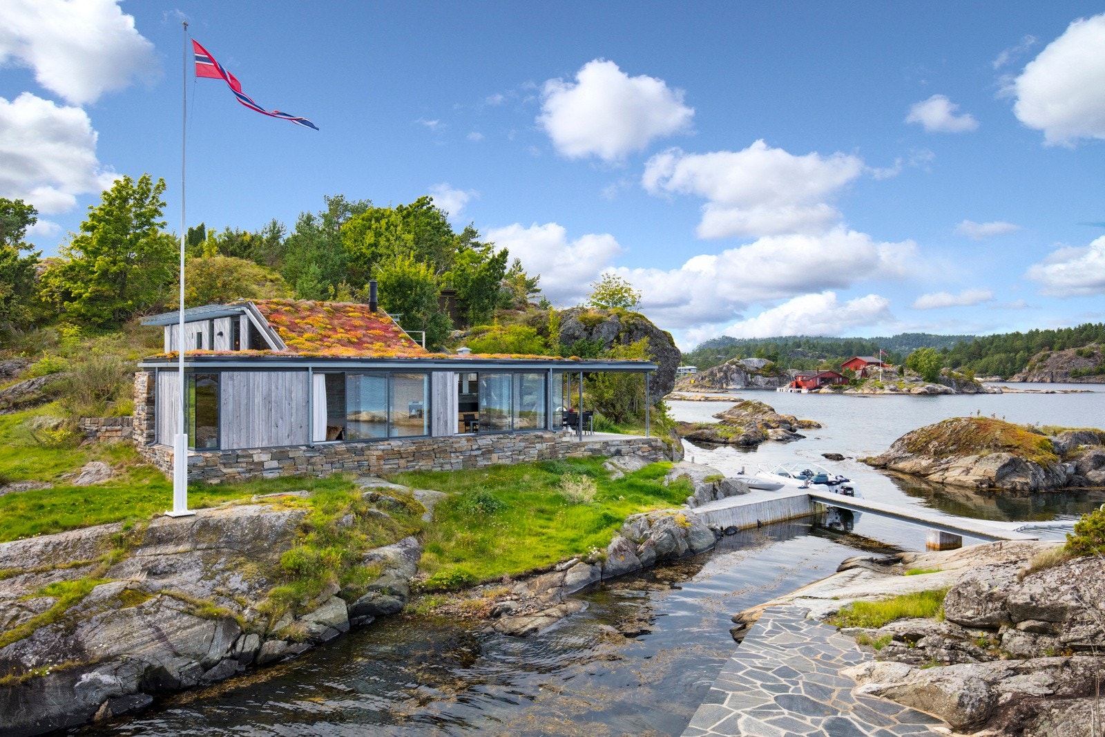 Hytta er plassert lavt i terrenget noe som bidrar til å skjerme for vær og vind. Galleribilde