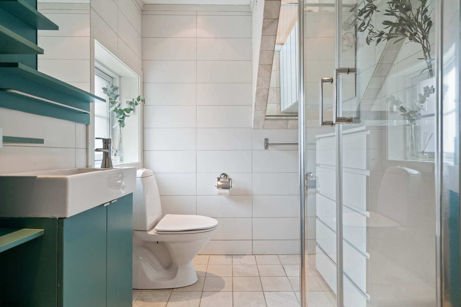 Badet er delikat flislagt og innredet med servant på innredning, toalett og dusjkabinett Galleribilde