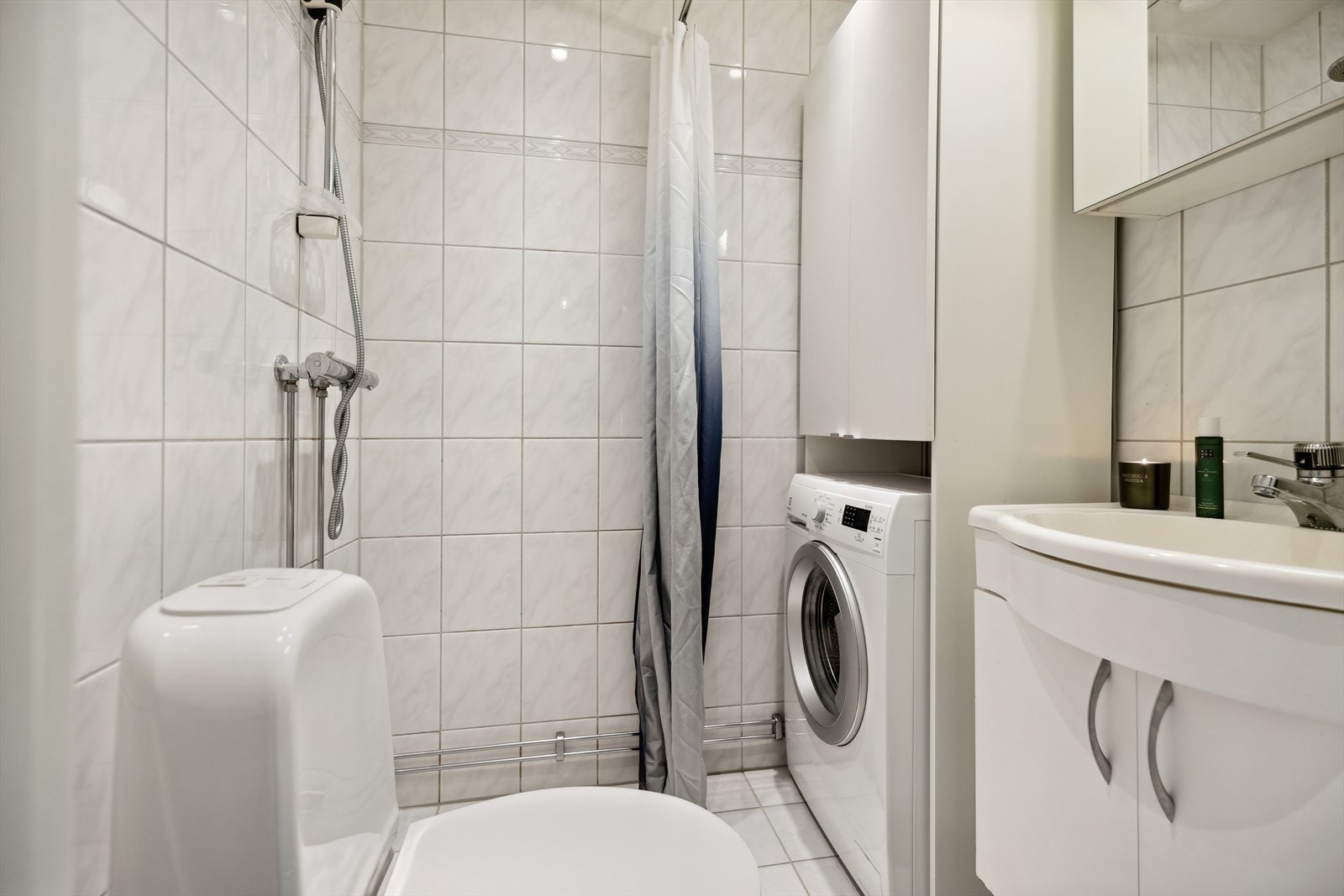 Innredningen består av består av frittstående wc, servant m/underskap, overskap m/speilfronter og overlys, åpen dusj m/forheng og opplegg for vaskemaskin. Galleribilde