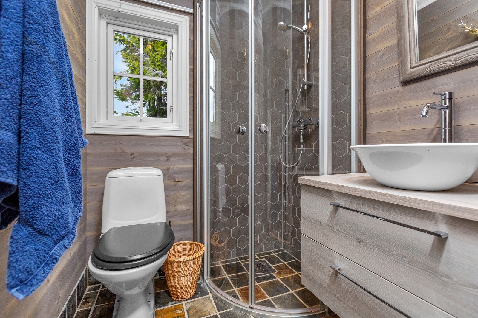 Bad nr 2 ligger i motsatt ende av hytta og har behandlet panel på veggene, flis i dusnisje og flislagt gulv. Galleribilde