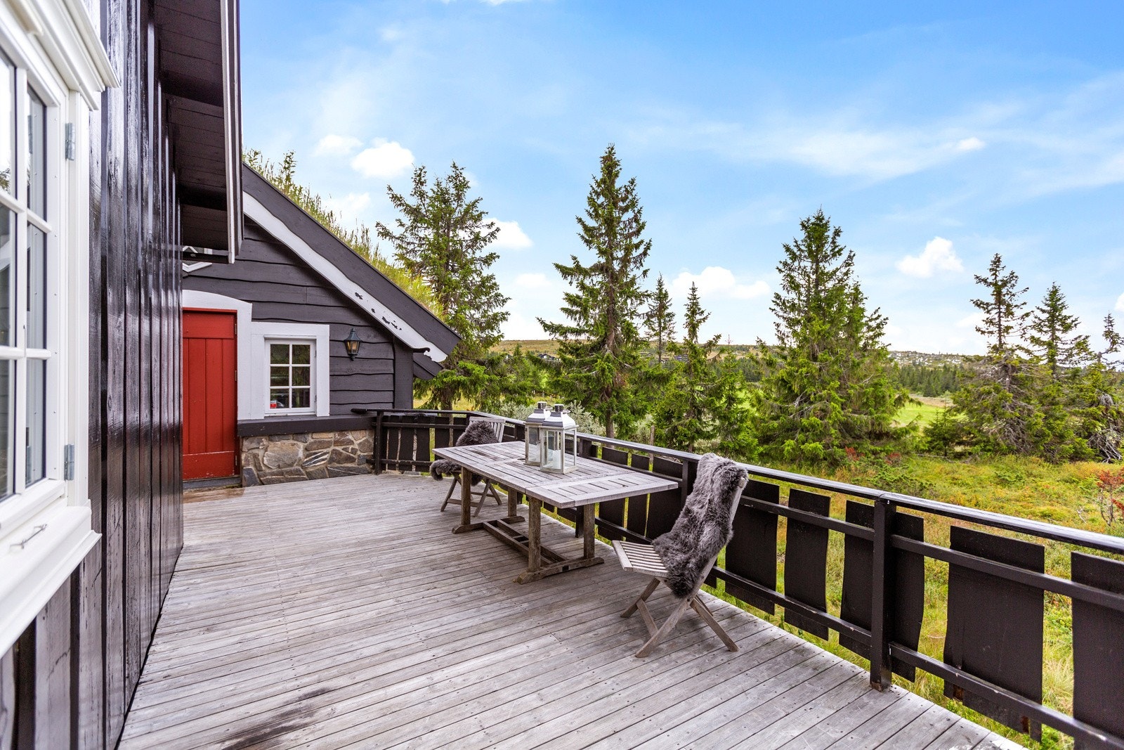 Stor veranda som strekker seg langs hele langsiden samt på sørsiden av hytta. Galleribilde