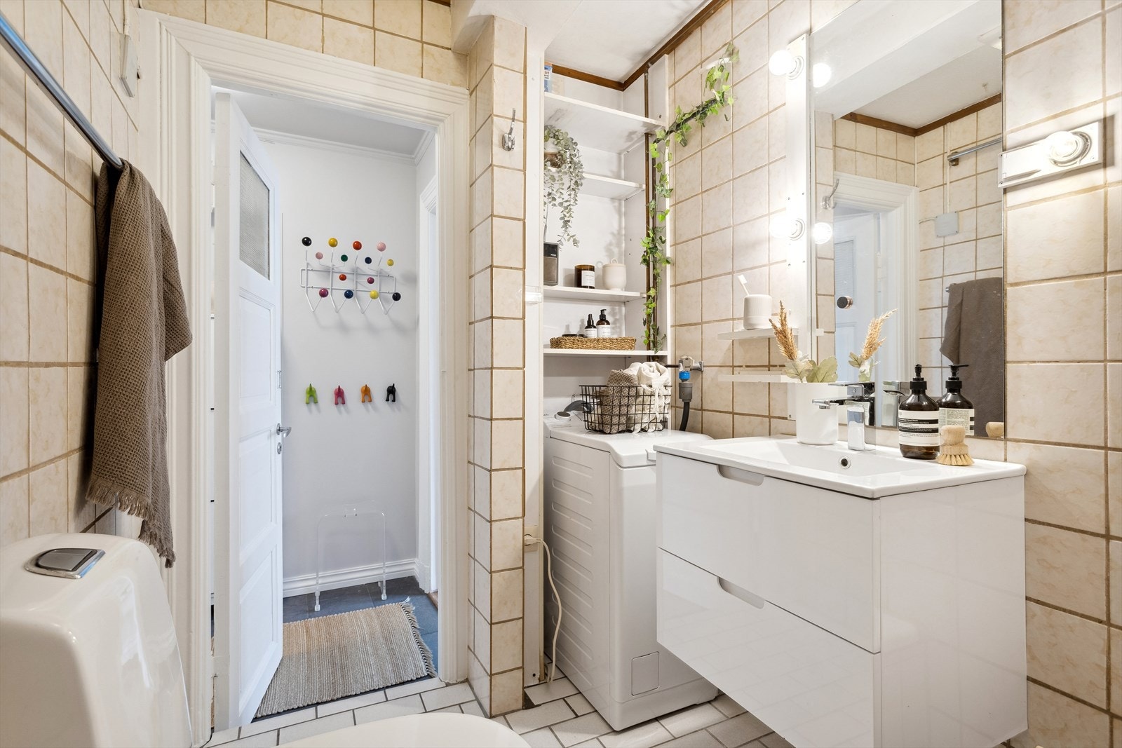 Flislagt bad med gulvvarme og innredet med badekar, frittstående toalett, opplegg for toppmatet vaskemaskin og nedfelt servant med underskuffer. Galleribilde