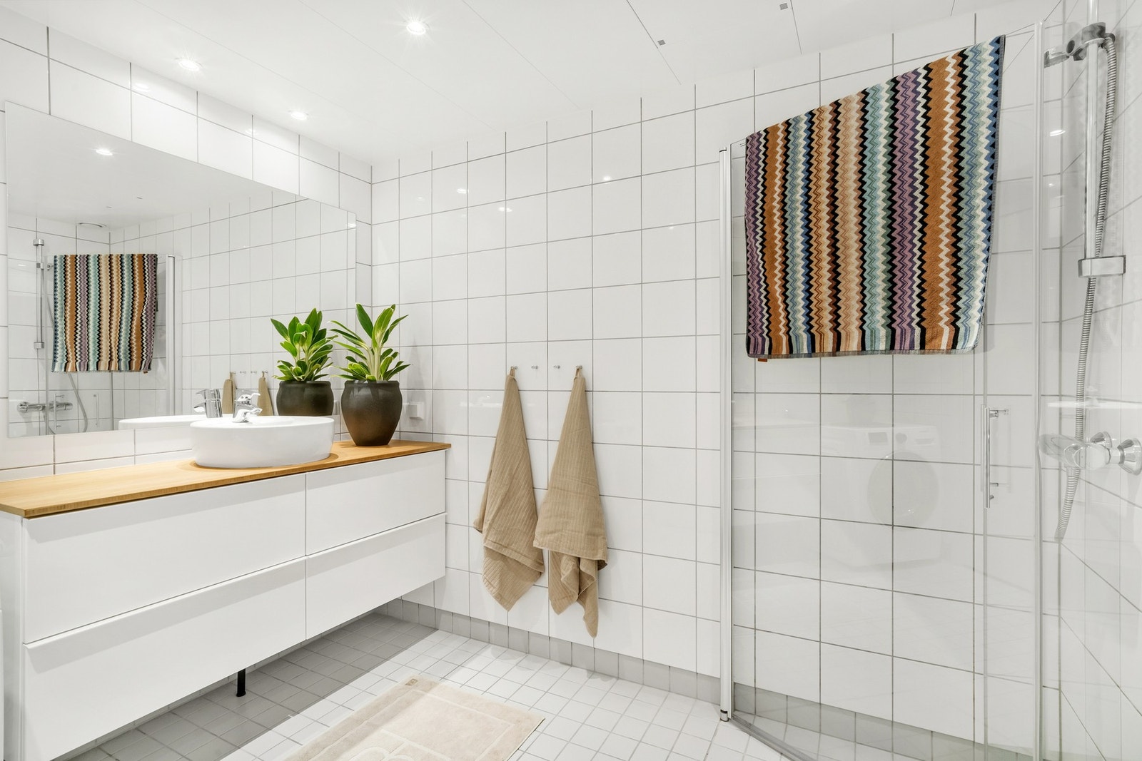 Flott flislagt bad med dusjhjørne, vegghengt innredning og WC. Galleribilde