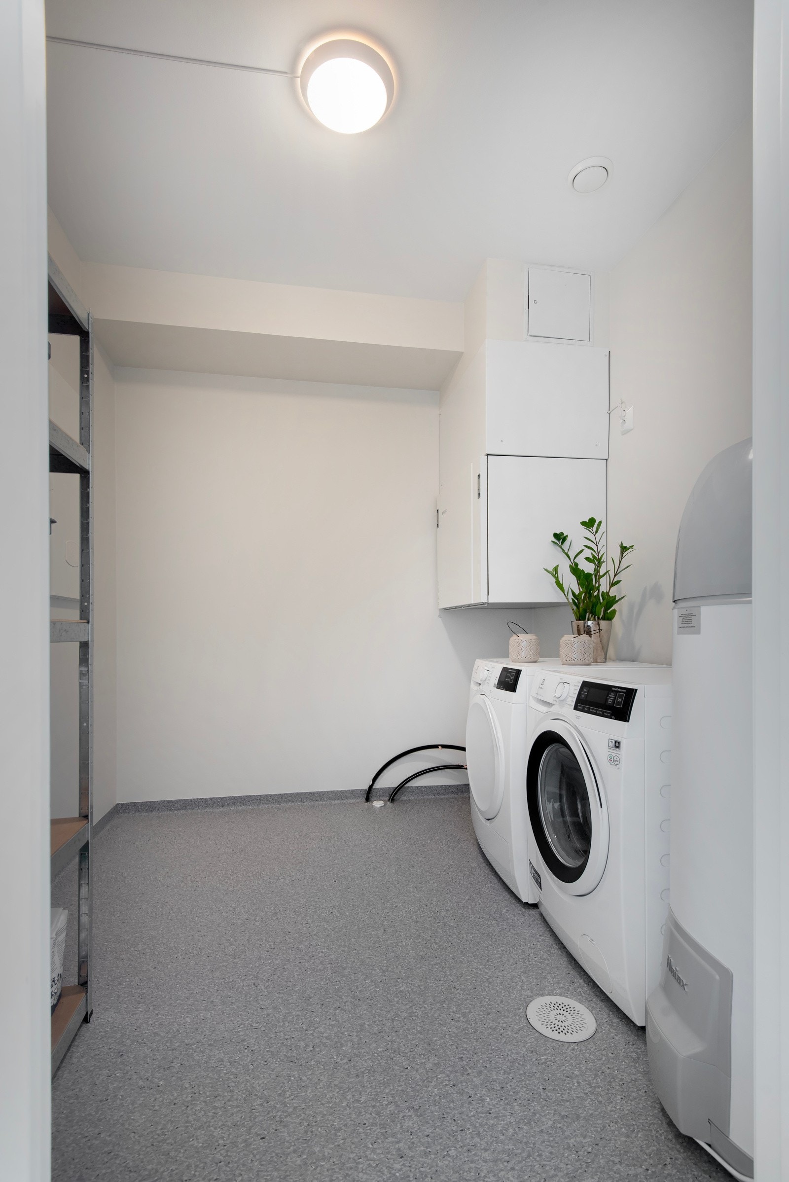 Et praktisk vaskerom med belegg på gulv. Opplegg for vaskemaskin. Her er også vv-bereder, teknisk utstyr som ventilasjonsanlegg som også har styringspanel. Galleribilde