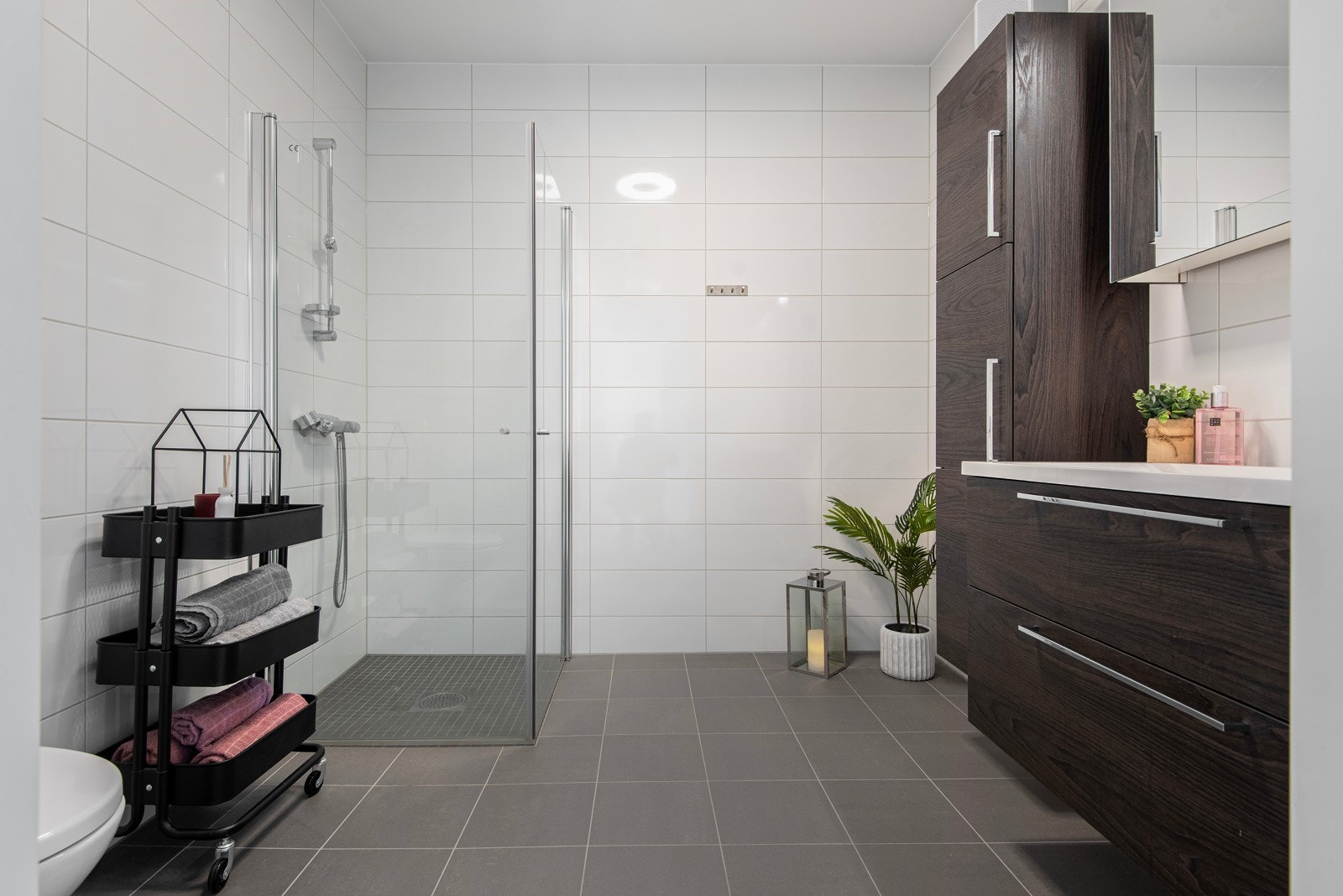 Badet er pent flislagt i varm og klassisk fargetone. Innrending med brunbeisede fronter på skap og skuffer. Heldekkende servantplate og speilskap med overliggende lys. Galleribilde