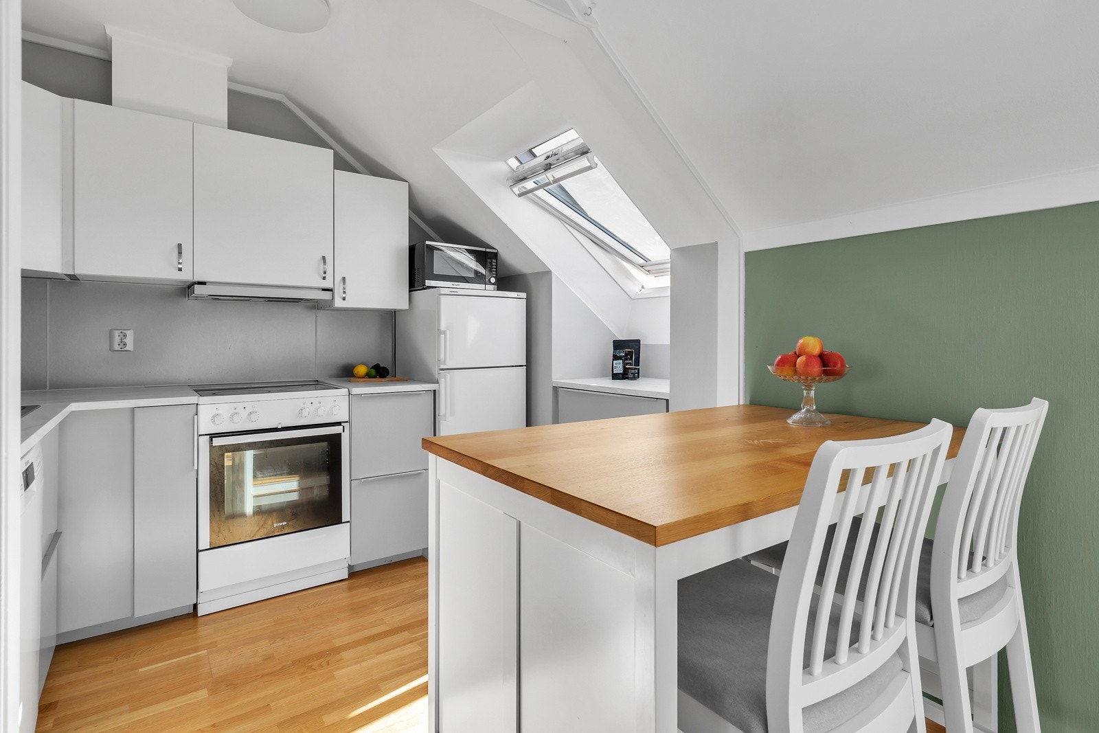 Flott lyst kjøkken med kjøkkenøy med plass til et par barstoler Galleribilde