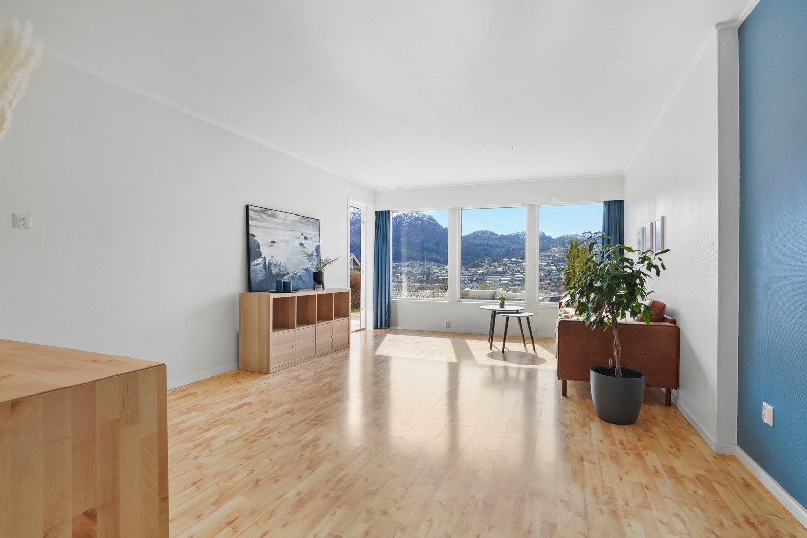 Stue med plass til flere sittegrupper og store vindu som vender mot sør - her er det også terrassedør ut til hagen Galleribilde