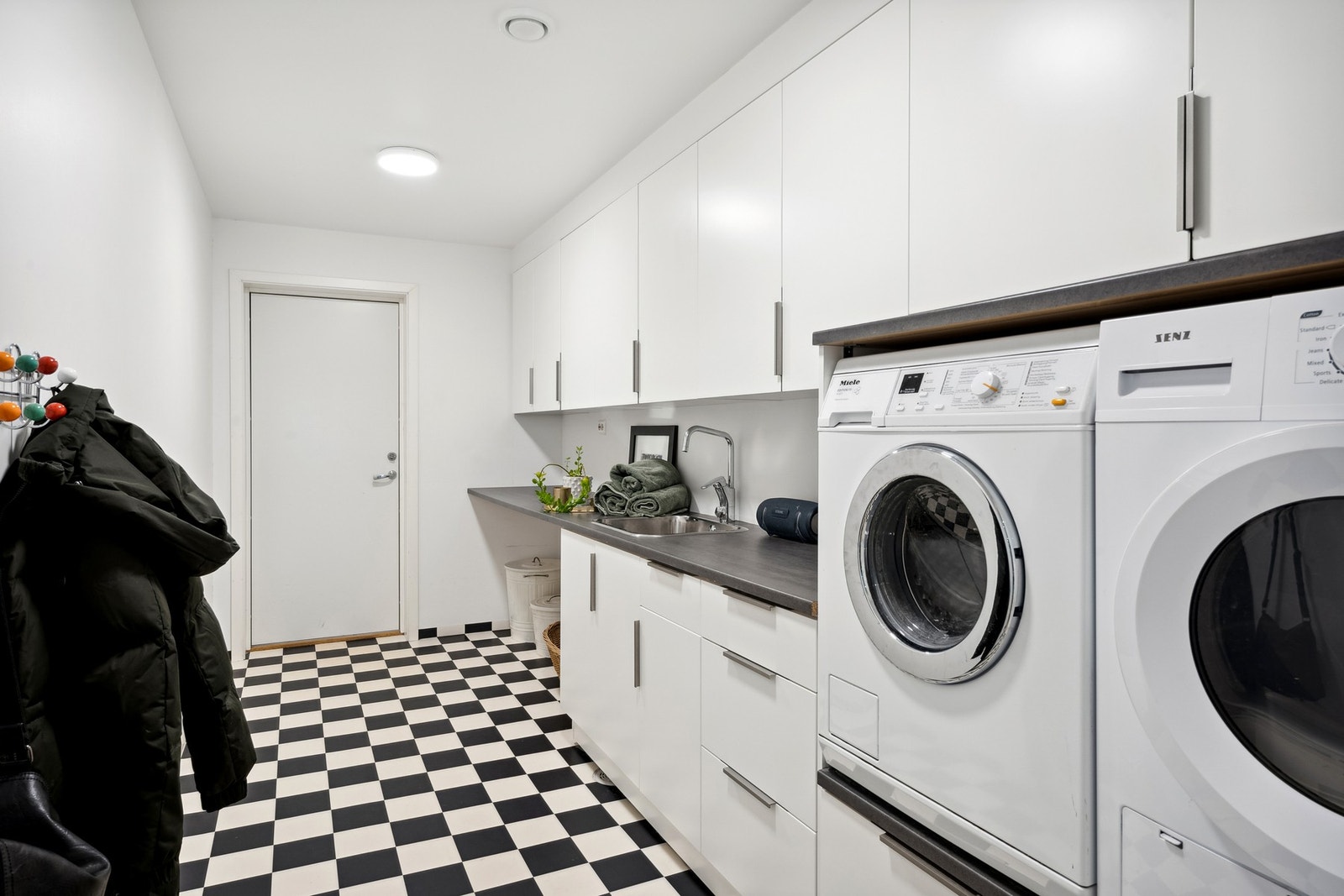 Stort og praktisk vaskerom med effektive arbeidsflater. Fra rommet er det direkte adkomst til garasje Galleribilde