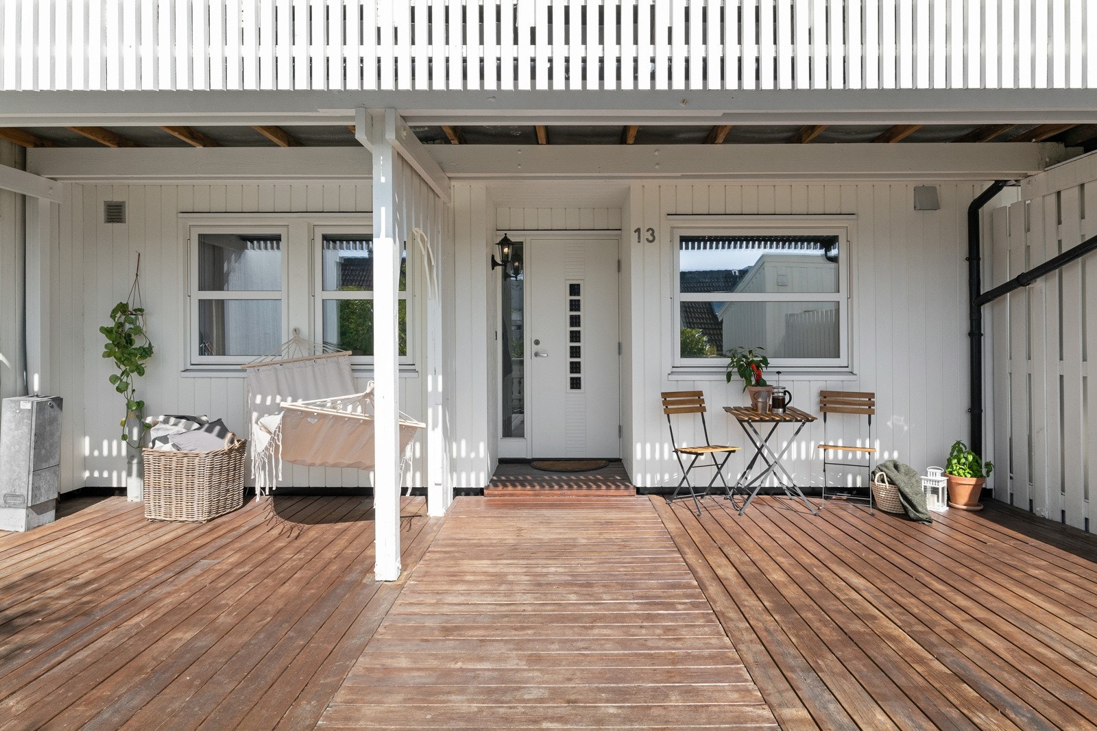 Stien fører til en stor terrasse med hvitt rekkverk og levegg mot nabo. Galleribilde
