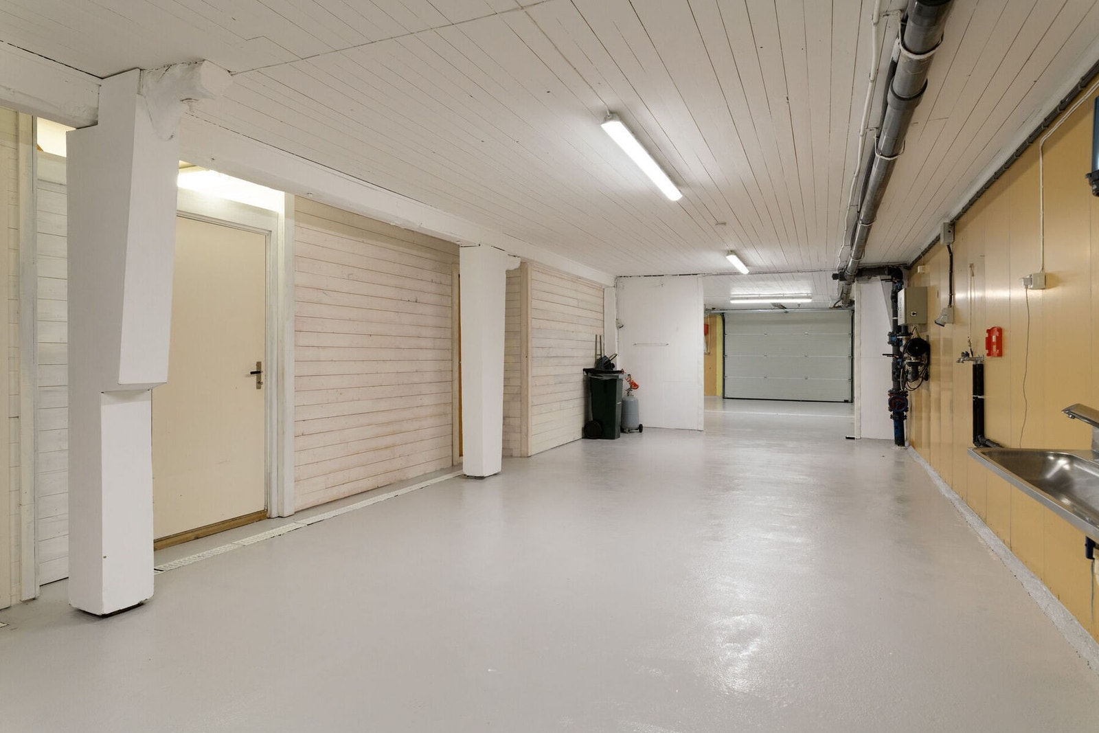 Underetasjen er renovert. Fra dette rommet når man tidligere produksjonsrom, kontor/butikk, omkledningsrom og verkstedrom. Vi ser mottak med port ut på kaia lengst bort på bildet. Galleribilde