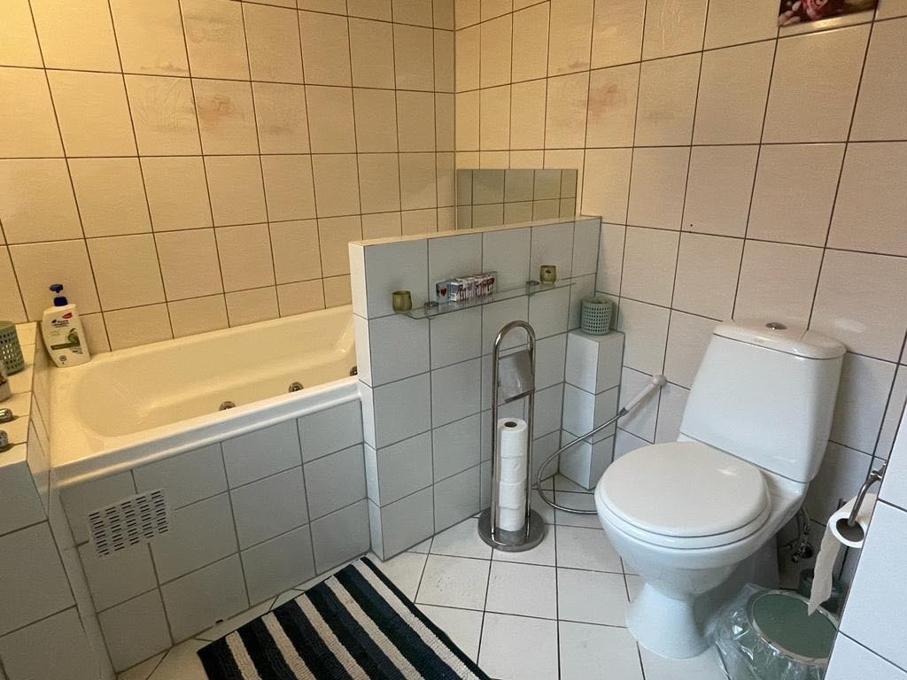 Bad 1 hel fliset og varmekabel på gulvet med både badekar og dusjkabinett Galleribilde