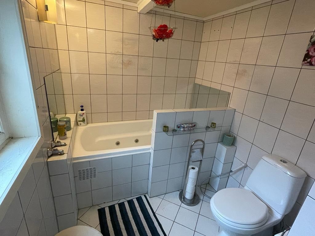 Bad 1- hel fliset og varmekabel på gulvet med både badekar og dusjkabinett Galleribilde