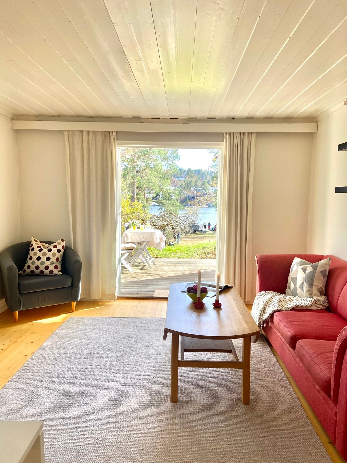 God plass til sofa. Utsikt mot hage og strand Galleribilde