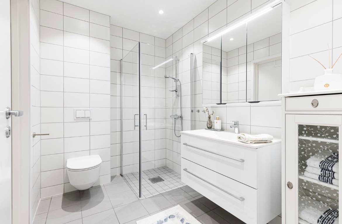 Badet er stilrent med hvite veggfliser og lysegrå gulvfliser. På badet er det gulvvarme og downlights i himlingen. Galleribilde